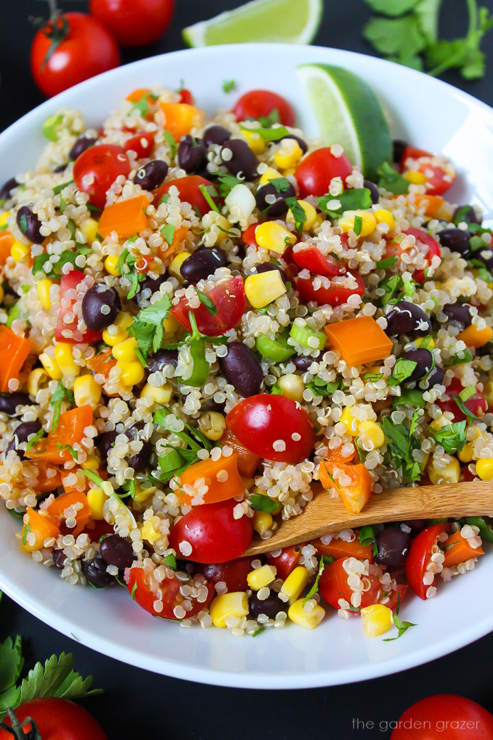 Close-up view of Mexican Quinoa Salad on a white plate with wooden serving spoon