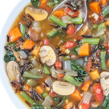 Vegan wild rice vegetable soup in a bowl with spoon