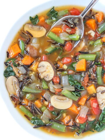 Vegan wild rice vegetable soup in a bowl with spoon