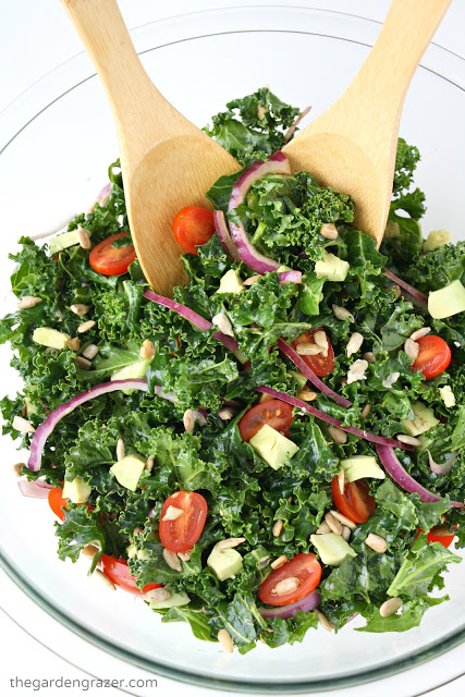 Marinated kale salad in a bowl with bamboo serving utensils