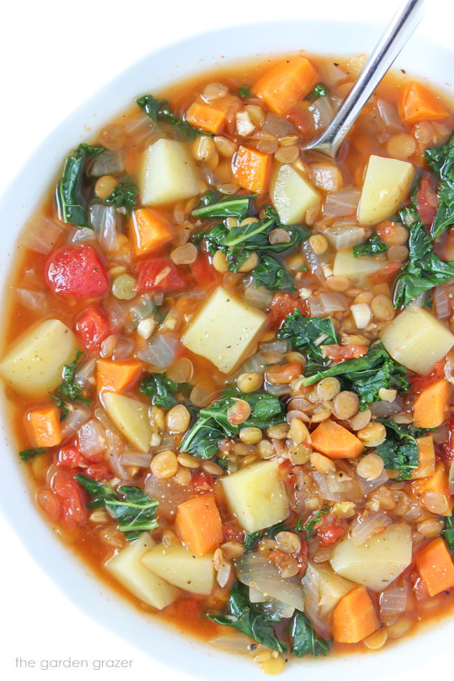 Bowl of vegan lentil kale potato soup with spoon