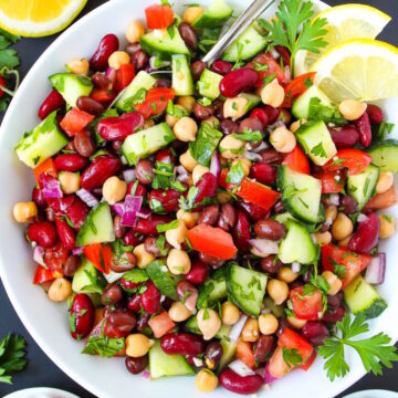 Overhead view of Mediterranean Three Bean Salad on a white plate with serving spoon
