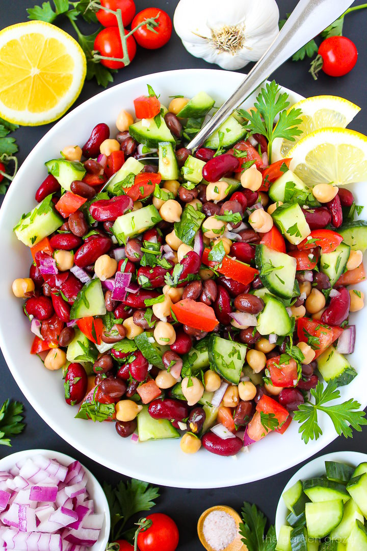 Overhead view of Mediterranean Three Bean Salad on a white plate with serving spoon