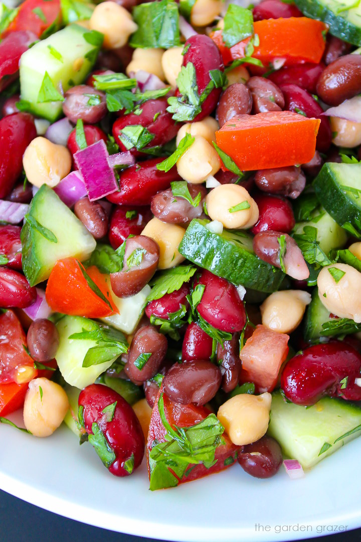 Close up view of Mediterranean Three Bean Salad with fresh herbs on a white plate