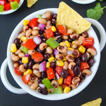 Overhead view of healthy Texas caviar in a white serving bowl with tortilla chip
