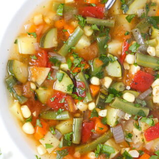 Bowl of vegan garden vegetable soup with fresh herbs