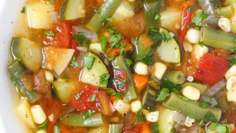 Bowl of vegan garden vegetable soup with fresh herbs