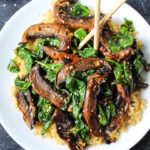 Sauteed spinach and Portobello mushrooms with garlic and ginger on a white serving plate with chopsticks