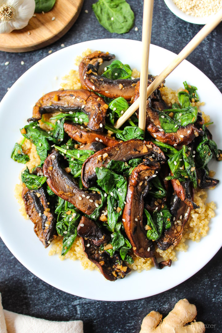 Sauteed spinach and Portobello mushrooms with garlic and ginger on a white serving plate with chopsticks