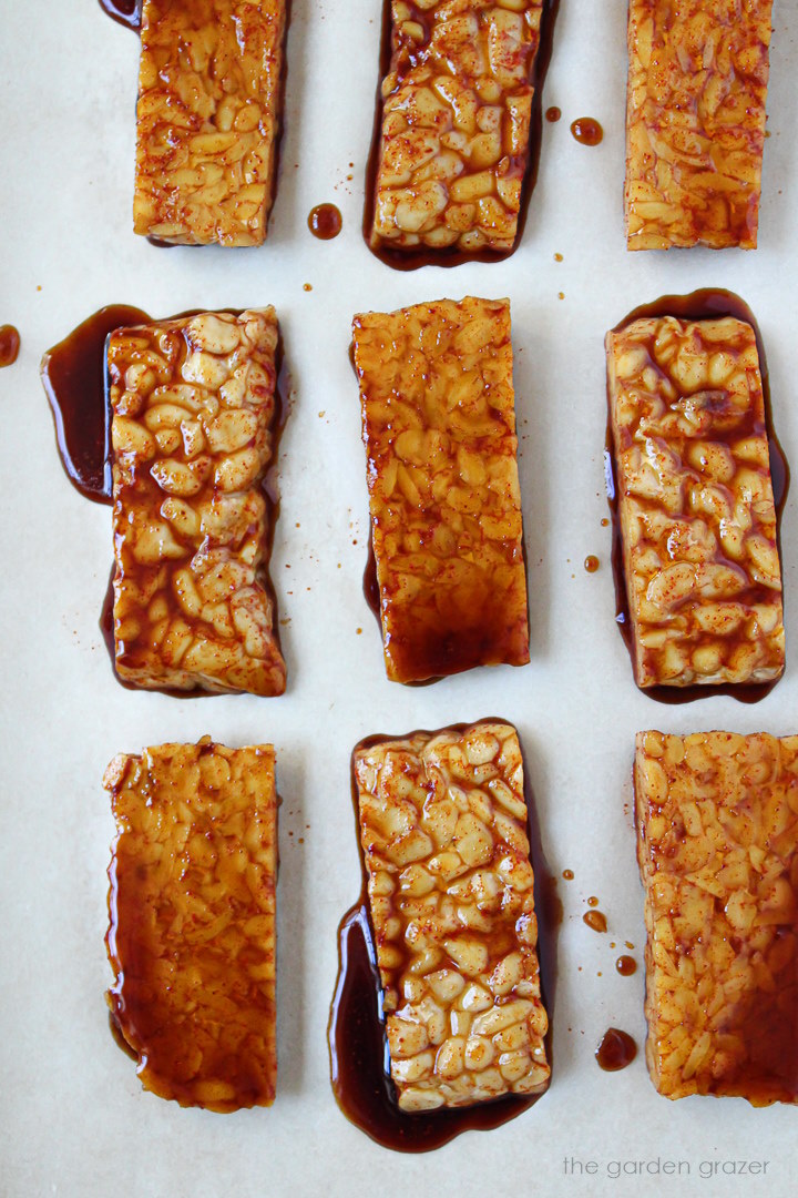 Marinated strips of tempeh bacon baking on a sheet pan