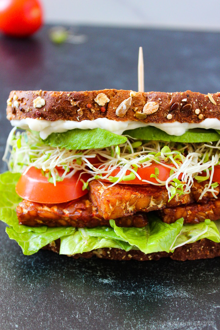 Close up view of a vegan TLT tempeh sandwich with avocado and sprouts
