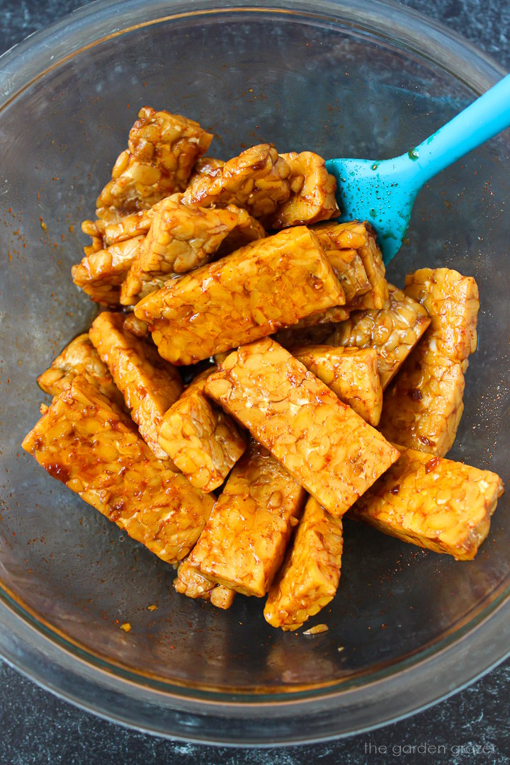 Preparing tempeh strips in a savory marinade before baking