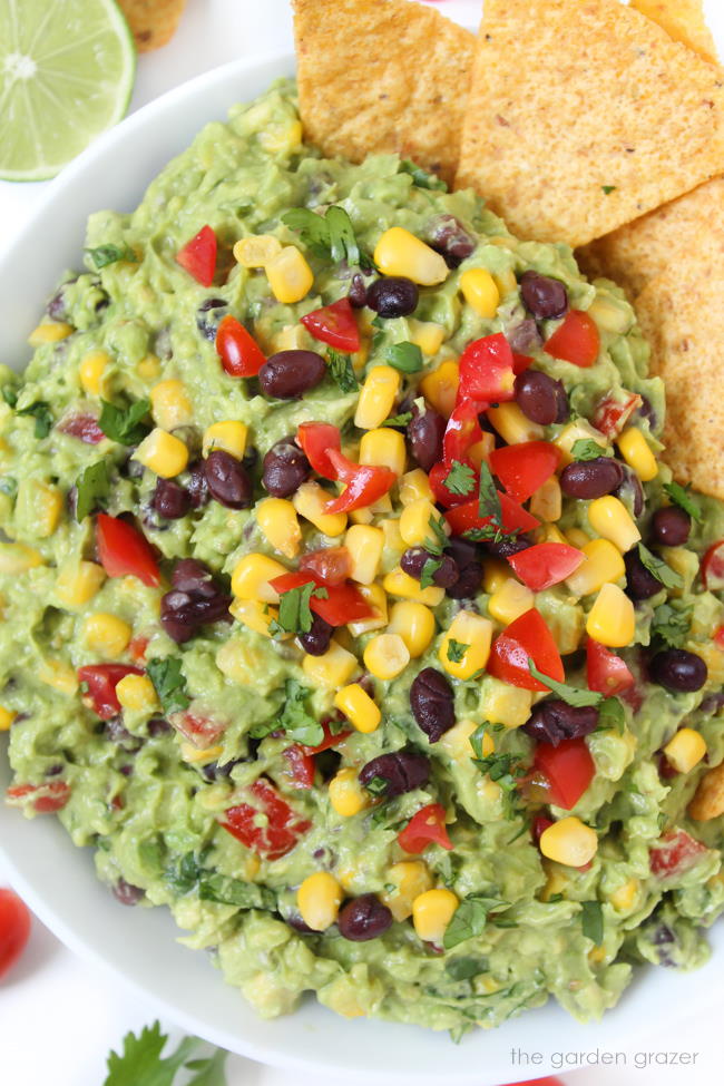 Bowl of black bean fiesta guacamole with cilantro and tomato