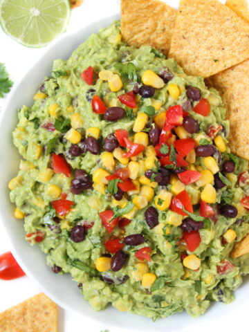 Black bean corn guacamole in a bowl with chips on the side