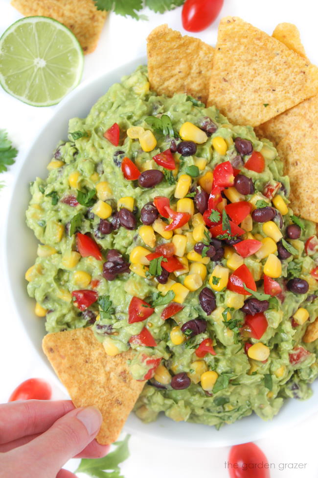 Tortilla chip dipping into black bean corn guacamole