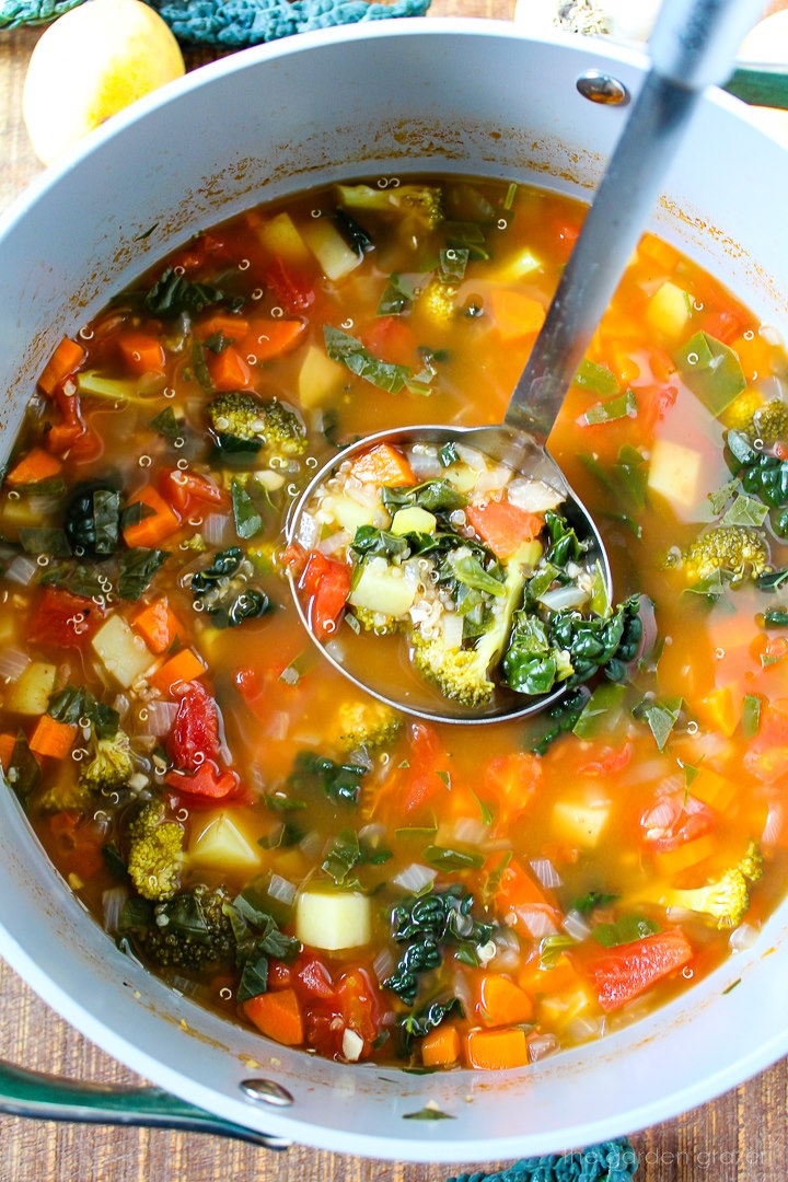 A ladle lifting up quinoa potato soup as it's cooking in a large pot