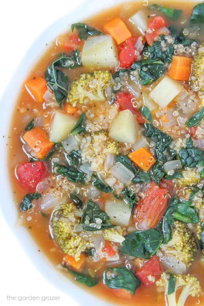 Vegan Quinoa Potato Soup with kale and spinach in a white bowl