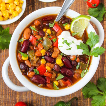 Three bean chili in a white serving bowl on a wooden table
