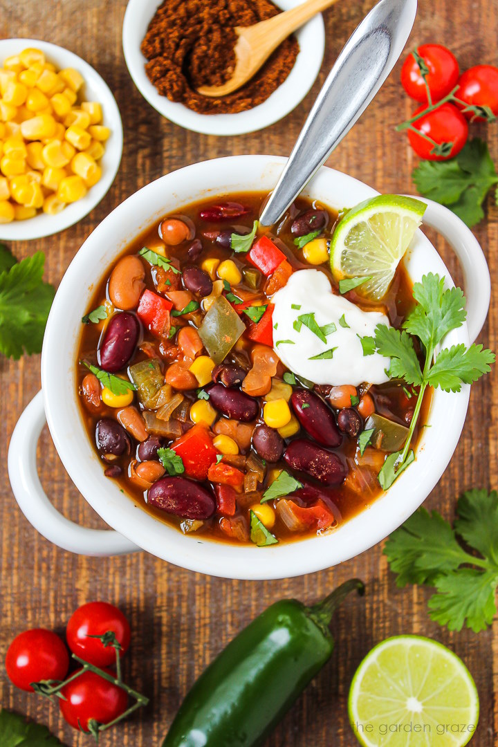 Three bean chili in a white serving bowl on a wooden table