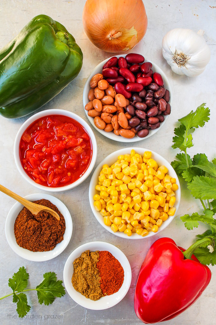 Bell peppers, onion, garlic, diced tomatoes, sweet corn, and spice ingredients laid out on a metal tray