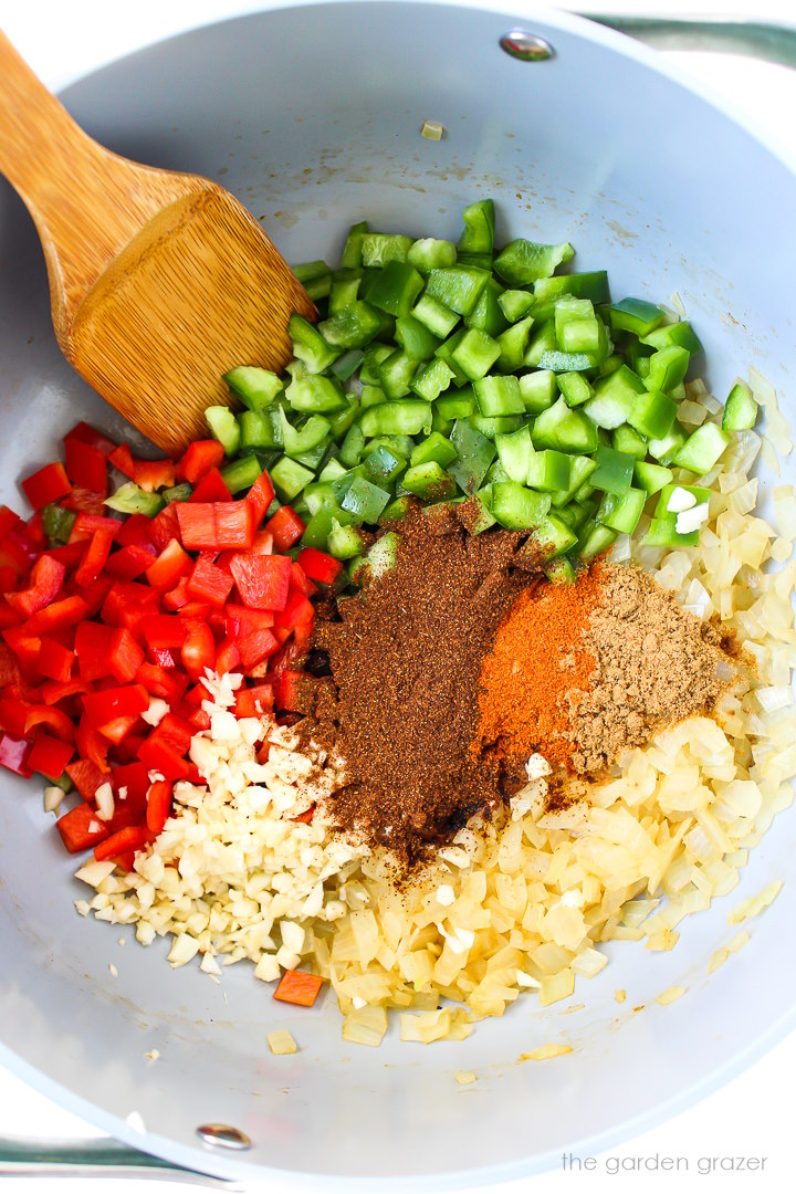 Overhead view of preparing bell pepper, onion, garlic, and spices in a large stockpot