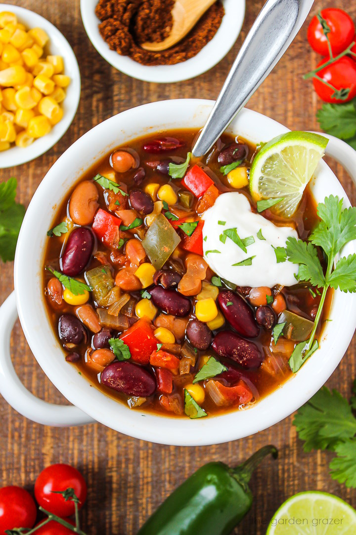 Close up view of vegan three bean chili in a white bowl with serving spoon