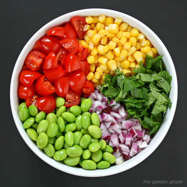 Ingredients for edamame tomato salad in a bowl