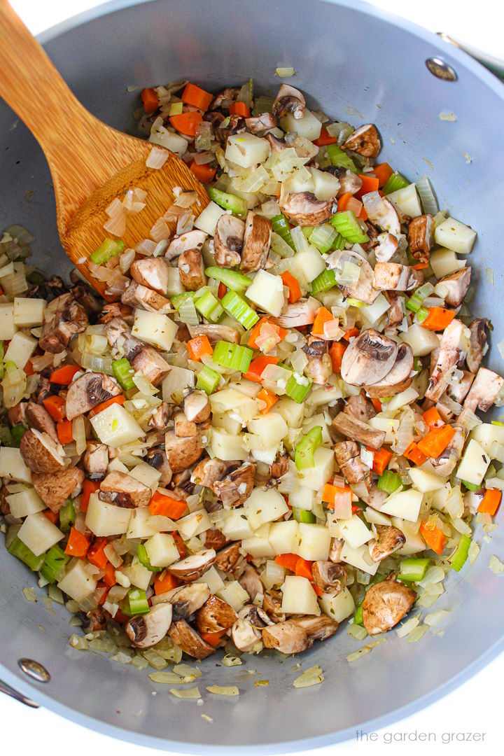 Cooking vegetables in a stockpot with wooden stirring spoon