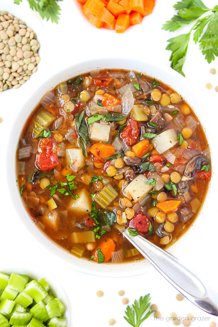 Lentil vegetable soup in a white bowl with spoon