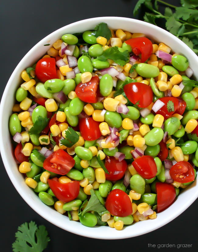 Bowl of edamame corn salad with tomato and cilantro
