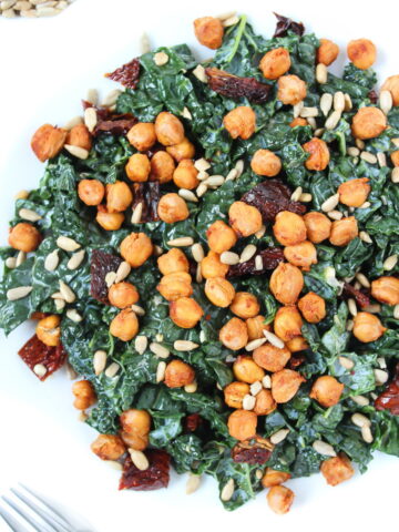 Roasted chickpea kale salad on a white plate with sun-dried tomatoes