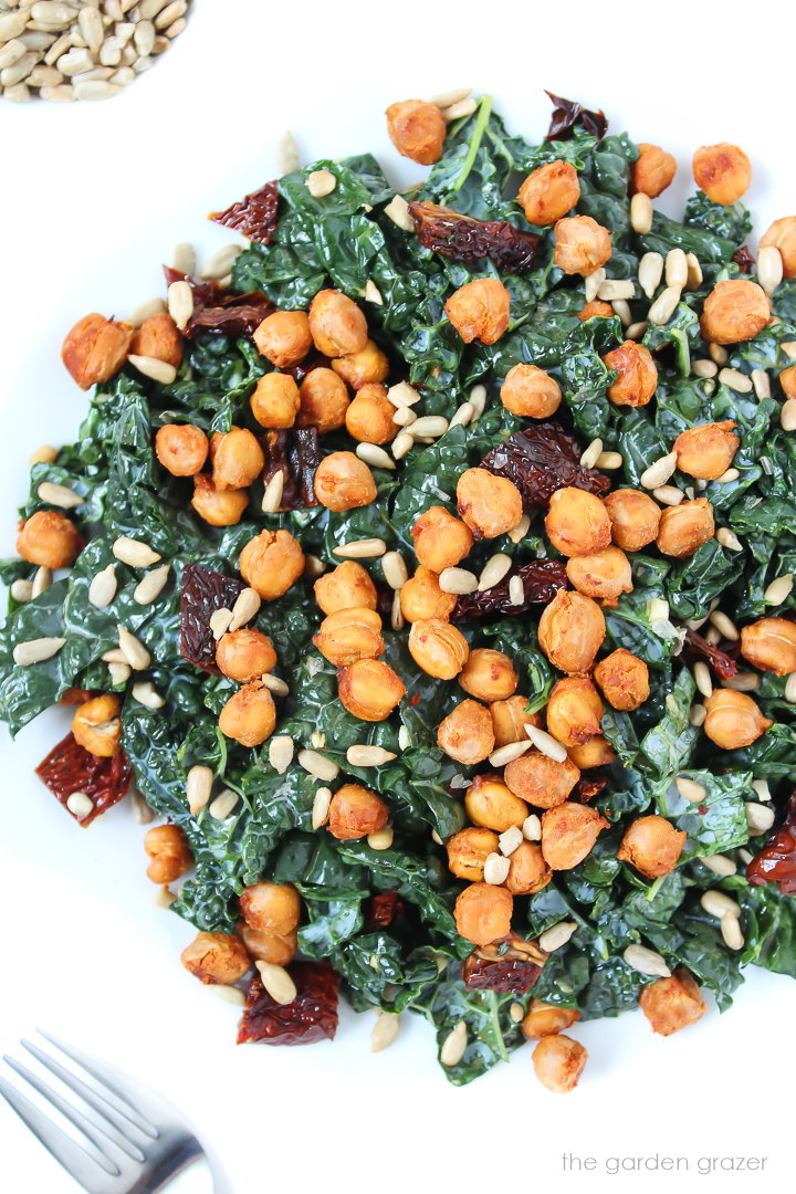 Roasted chickpea kale salad on a white plate with sun-dried tomatoes