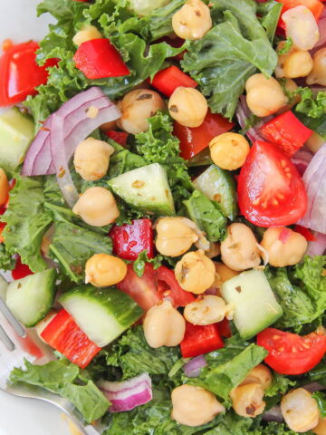 Greek-style kale salad with marinated chickpeas on a white plate