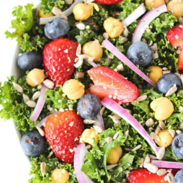 Bowl of kale power salad with berries, onions, and chia seed dressing