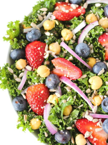 Bowl of kale power salad with berries, onions, and chia seed dressing
