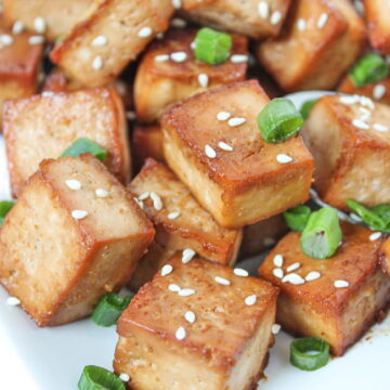 Cubes of easy baked marinated tofu on a plate with sesame seeds