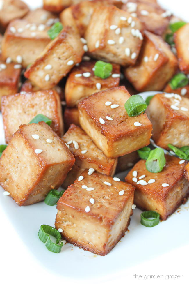 Cubes of easy baked marinated tofu on a plate with sesame seeds