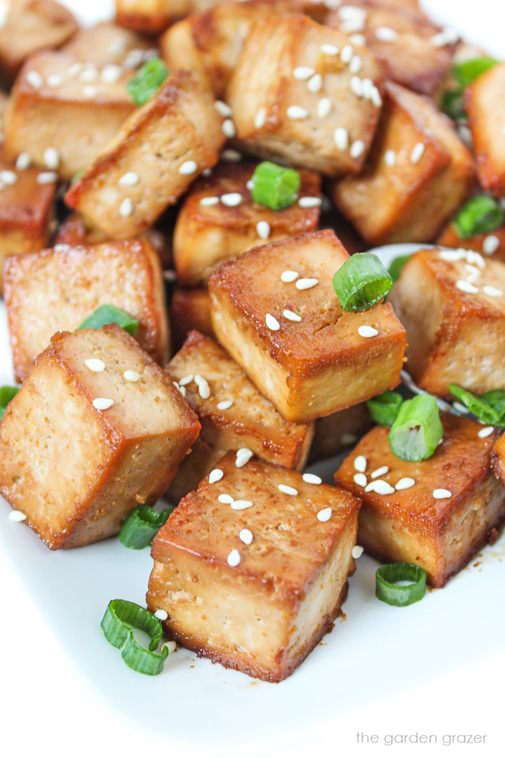 Close up view of easy baked savory tofu garnished with sesame seeds and green onion
