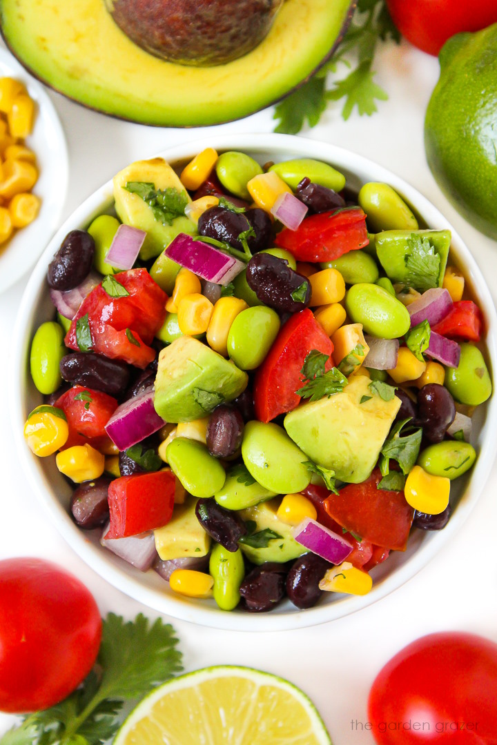 Avocado edamame salad with black beans and tomatoes in a small white bowl