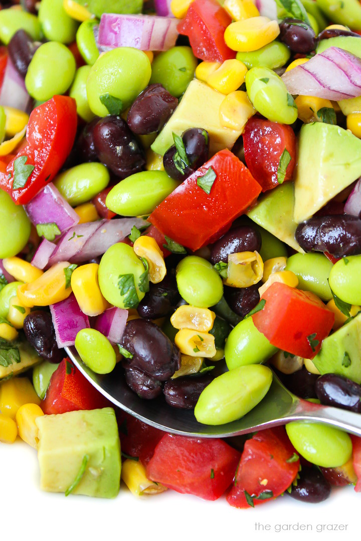 Close up view of black bean edamame salad with avocado with serving spoon