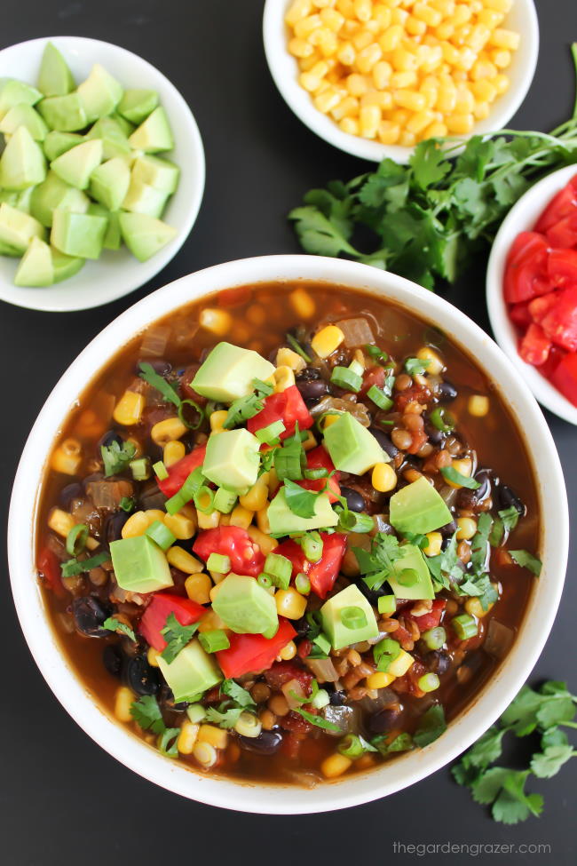 Bowl of black bean lentil taco soup with avocado, corn, and tomatoes