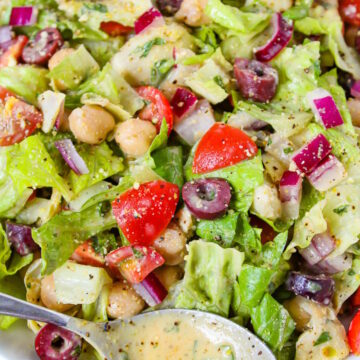 Close-up view of Vegan Italian Chopped Salad in a white bowl tossed with dressing