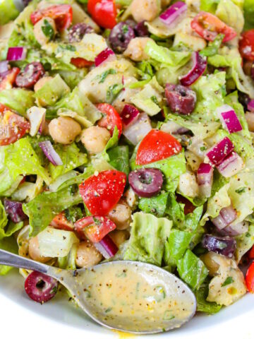 Close-up view of Vegan Italian Chopped Salad in a white bowl tossed with dressing