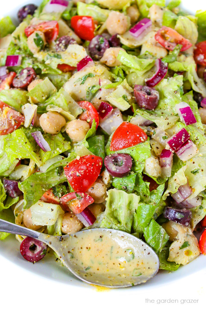 Close-up view of Vegan Italian Chopped Salad in a white bowl tossed with dressing