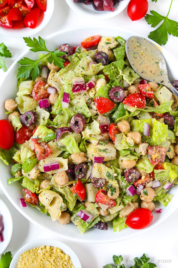 Overhead view of Vegan Italian Chopped Salad in a large white bowl with serving spoon