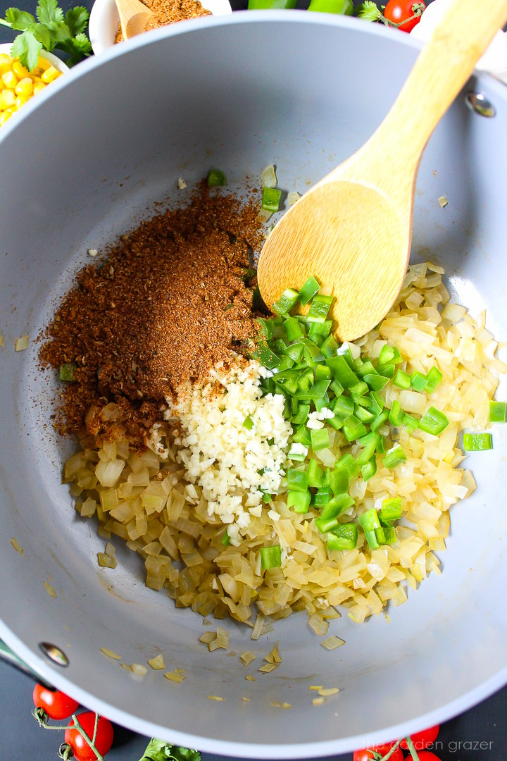 Overhead view of preparing onion, garlic, jalapeno, and taco seasoning in a large pot