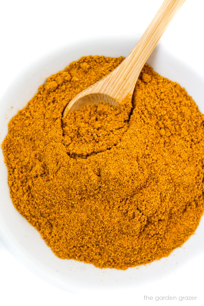 Dry curry powder in a small white bowl with bamboo spoon