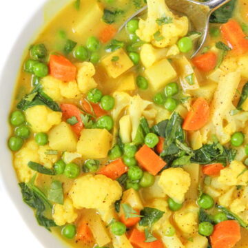 Bowl of vegan coconut curry soup with carrot, potato, and cauliflower