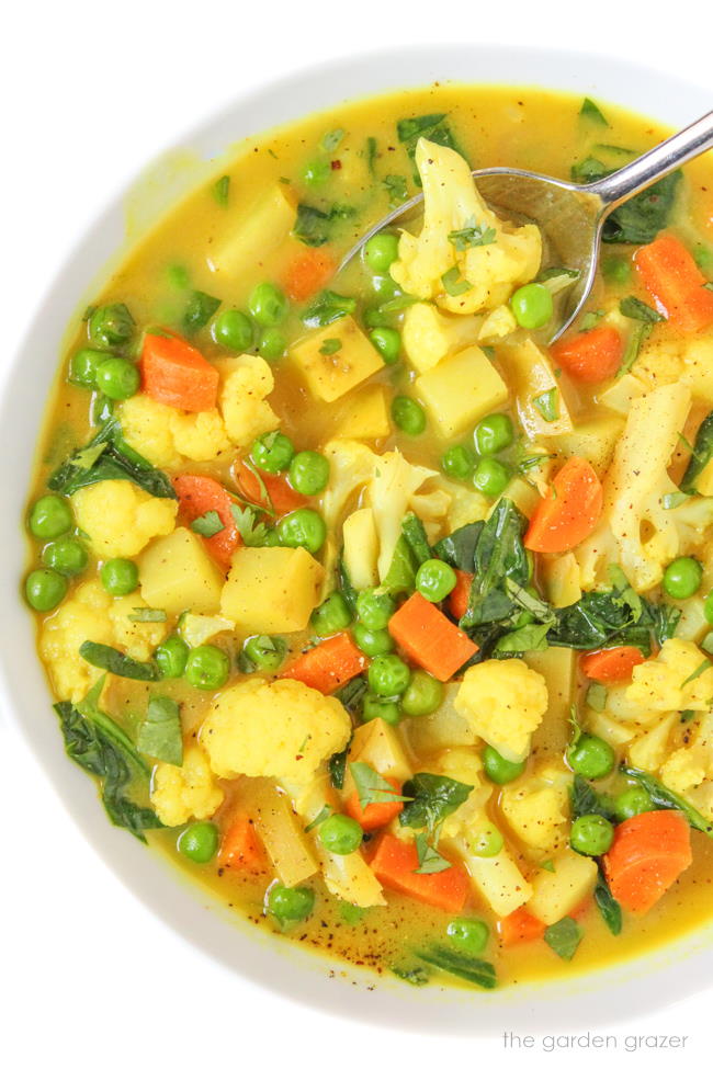 Bowl of vegan coconut curry soup with carrot, potato, and cauliflower