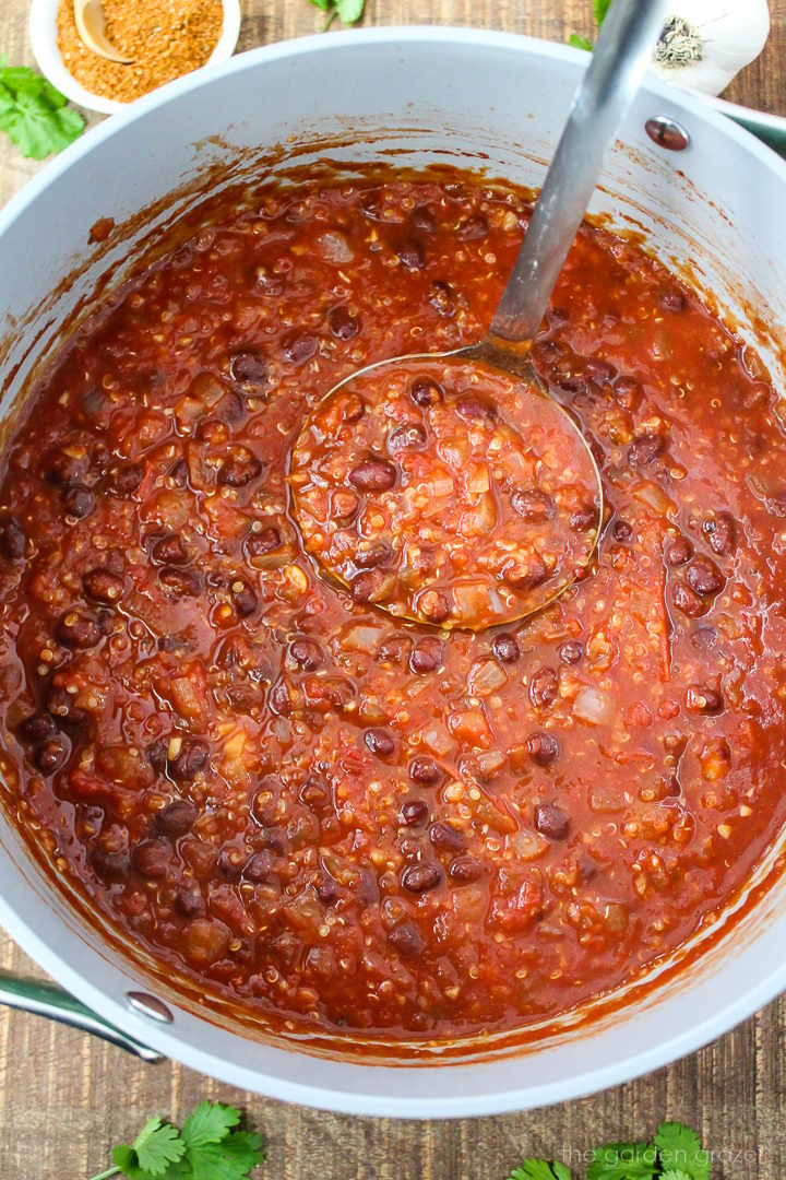 Overhead view of smoky chipotle black bean quinoa chili in a large pot with soup ladle